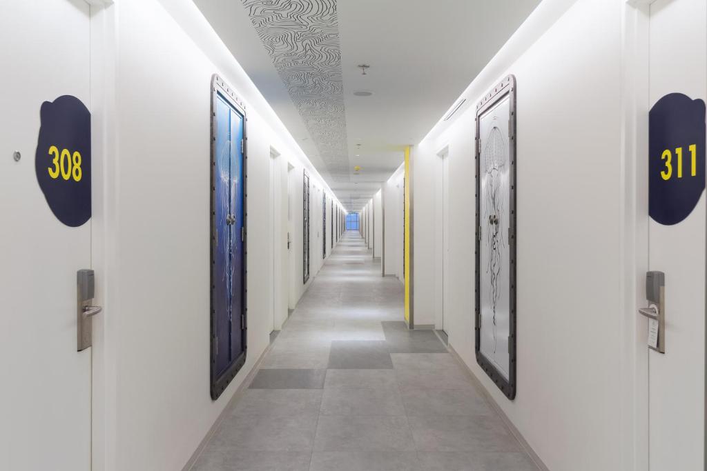 a corridor with white walls and a long hallway with doors at YELLO Hotel Kuta Beachwalk Bali in Kuta