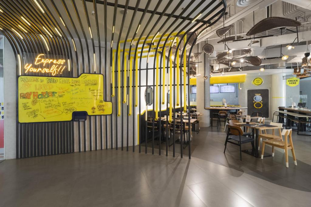 a restaurant with tables and chairs and a yellow sign at YELLO Hotel Kuta Beachwalk Bali in Kuta