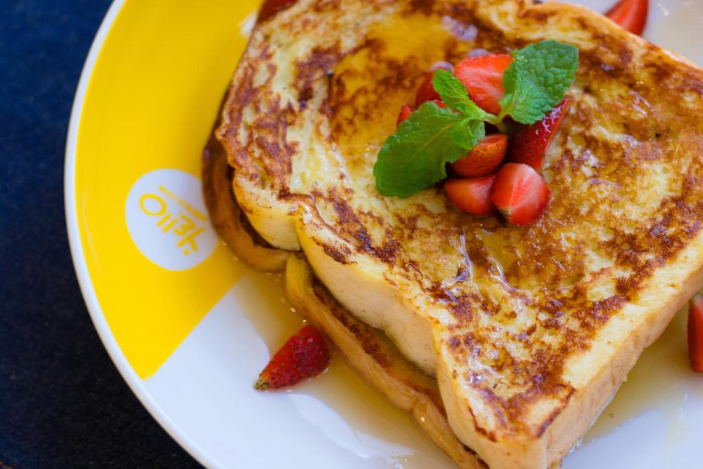 a plate with a sandwich with strawberries and mint on it at YELLO Hotel Kuta Beachwalk Bali in Kuta