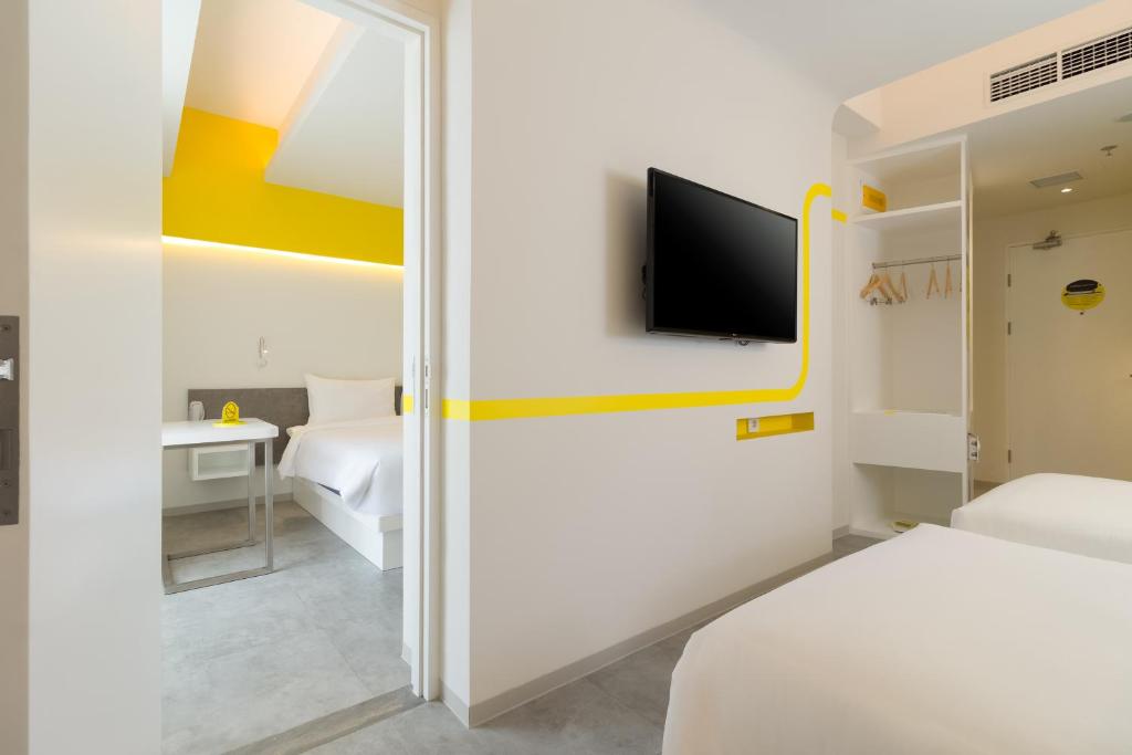 a room with two beds and a tv in it at YELLO Hotel Kuta Beachwalk Bali in Kuta