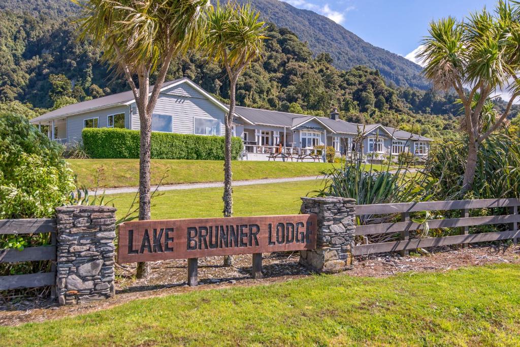 a sign in front of a house with palm trees at Lake Brunner Eco Lodge in Moana