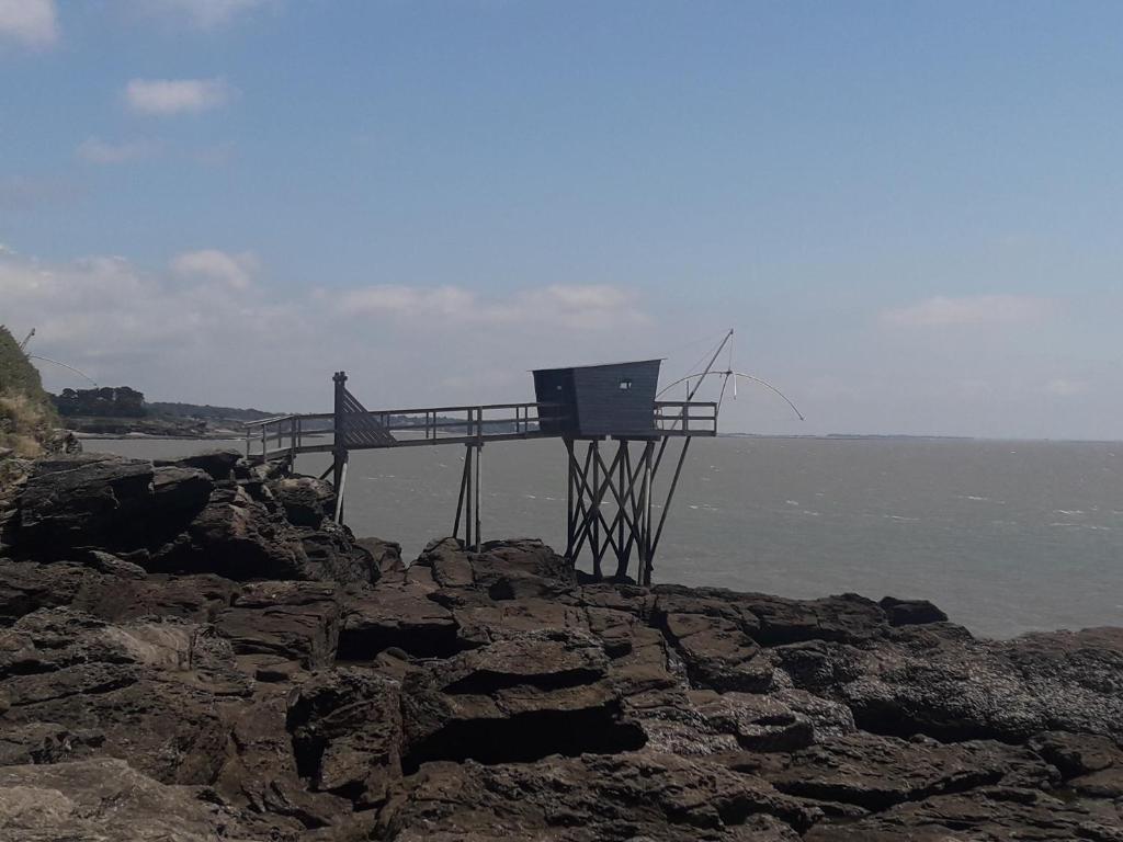 uma pessoa de pé sobre um calçadão sobre as rochas perto do oceano em maison tartifume em Pornic