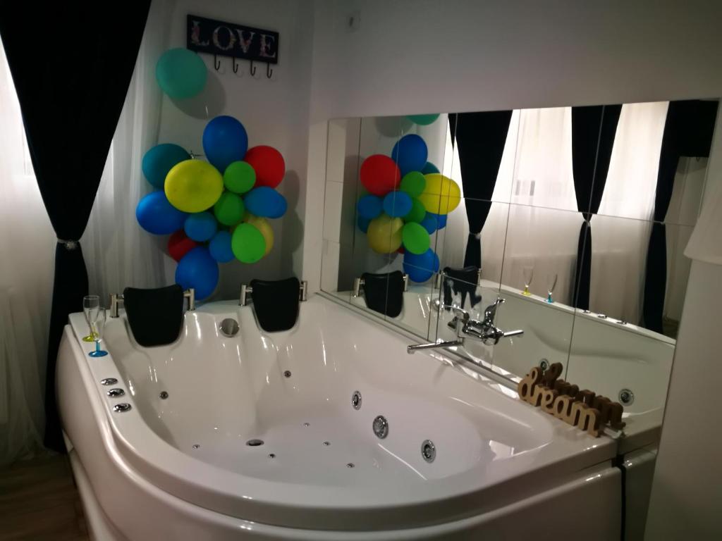 a bath tub with balloons in front of a mirror at Iași Jacuzzi Apartment F in Iaşi