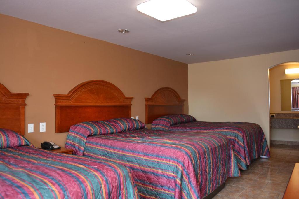 a hotel room with two beds with striped sheets at El Camino Motel in Beeville