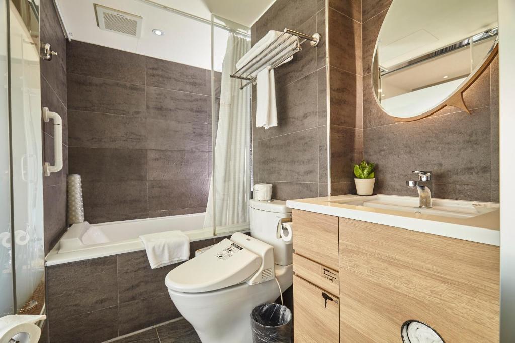 a bathroom with a toilet and a sink and a mirror at Simple + Hotel in Taipei