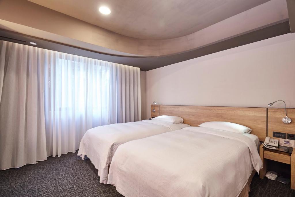 a hotel room with two beds and a window at Simple + Hotel in Taipei