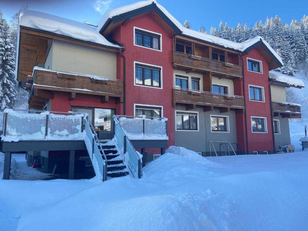 un gran edificio rojo con nieve en el suelo en Haus Birnbacher, en Mühlbach am Hochkönig