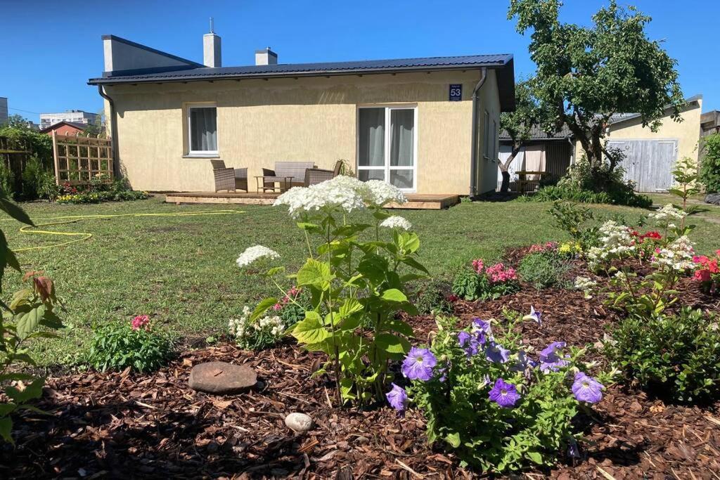 a garden with flowers in front of a house at Cozy family house in Ventspils