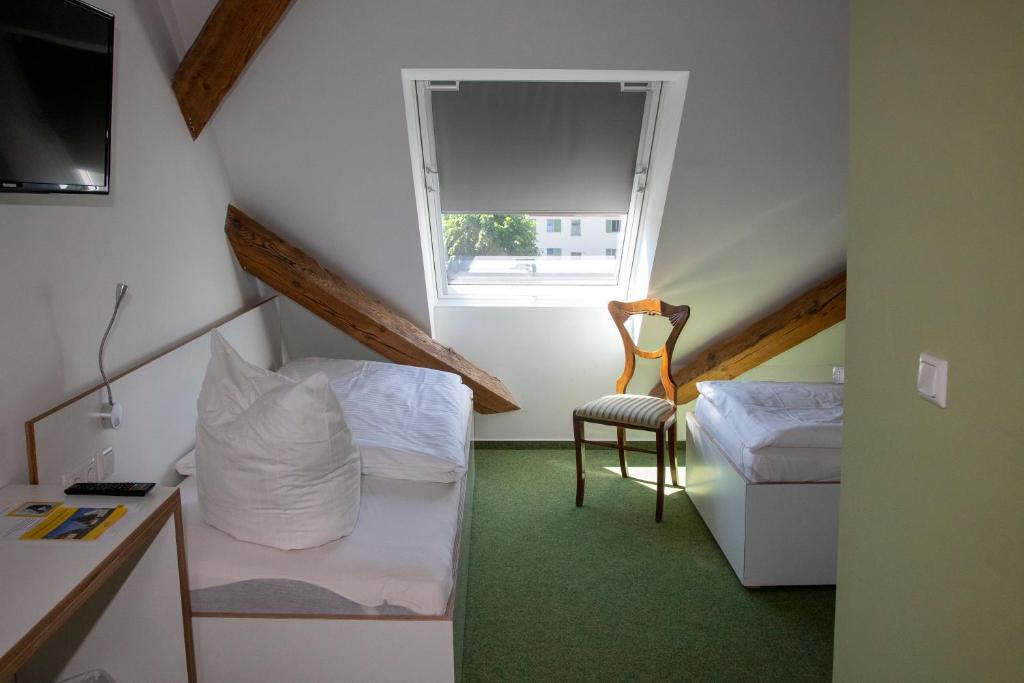 a small room with two beds and a chair at Gästehaus Reckahn der Rochow Akademie in Reckahn