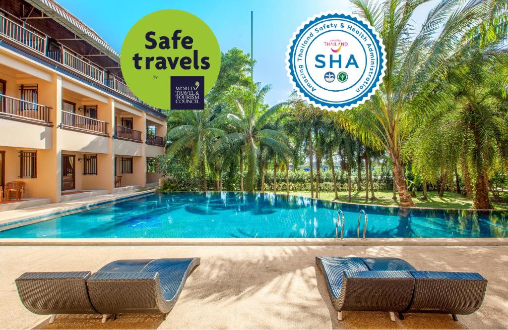 a swimming pool at a resort with a sign that says safe travels at Khaolak Mohin Tara Resort - SHA Certified in Khao Lak