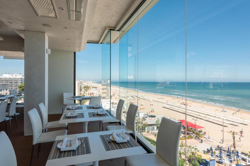 ein Restaurant mit Tischen und Stühlen und Blick auf den Strand in der Unterkunft Hotel Commodore in Riccione