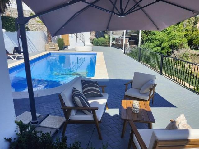 um pátio com cadeiras e um guarda-sol junto a uma piscina em Duende Marbella em Marbella