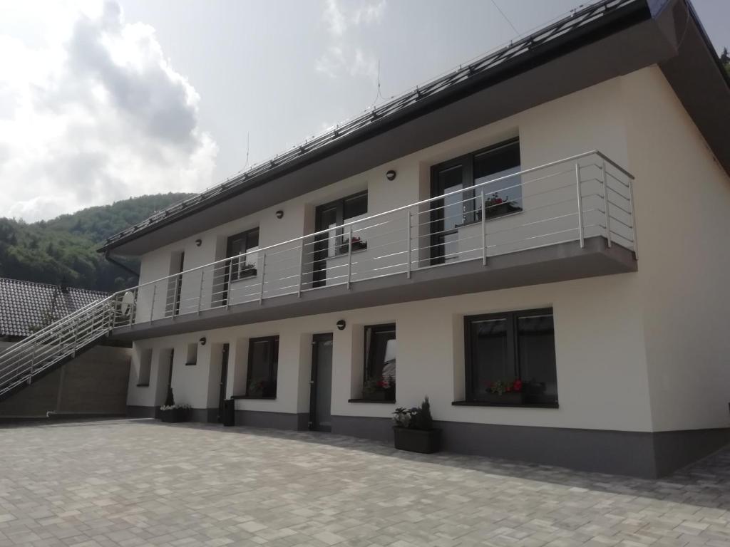 a white building with a balcony and a staircase at Vila Lada in Dedinky