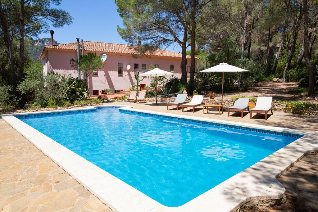 una piscina con sillas y sombrillas frente a una casa en AldeaMia, Forest, mountain view, beach at 8 min, en Vilanova d'Escornalbou