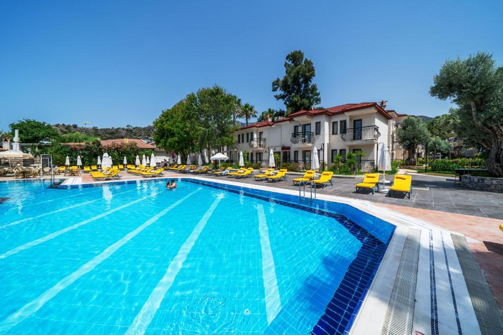 a large swimming pool with yellow chairs and a hotel at Sundia By Liberty Oludeniz in Oludeniz