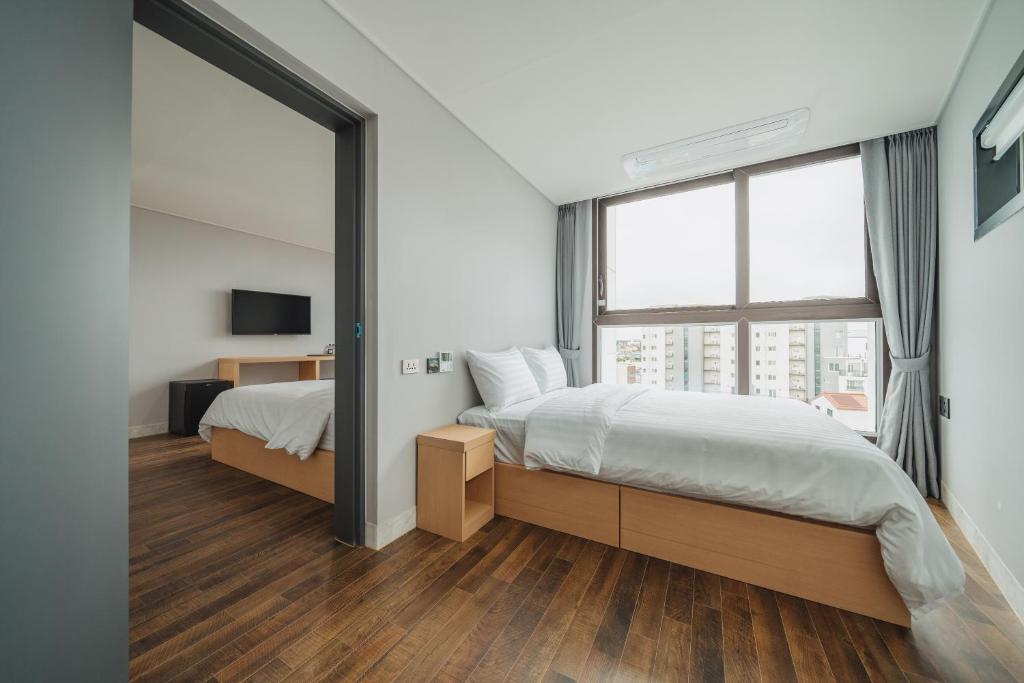 um quarto com 2 camas e uma grande janela em Aroomi Hotel Hyupjae em Jeju