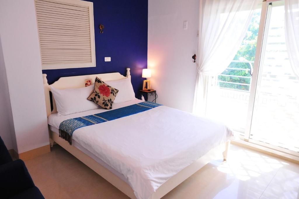 a bedroom with a white bed with a blue wall at 花蓮觀月民宿-寵物友善-含車位 in Hualien City