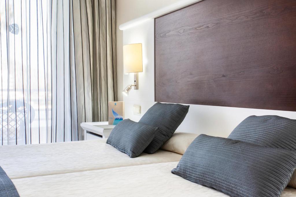a bedroom with a bed with two blue pillows at Grupotel Amapola in Playa de Muro