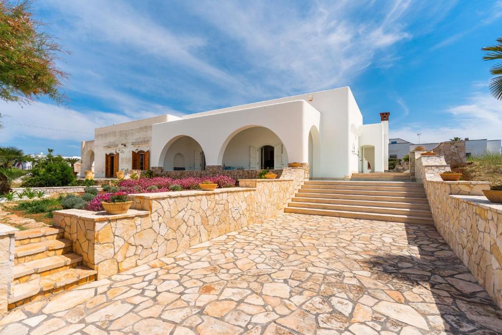 a stone walkway leading to a white building at Villa Giusy by BarbarHouse in Marina di Mancaversa