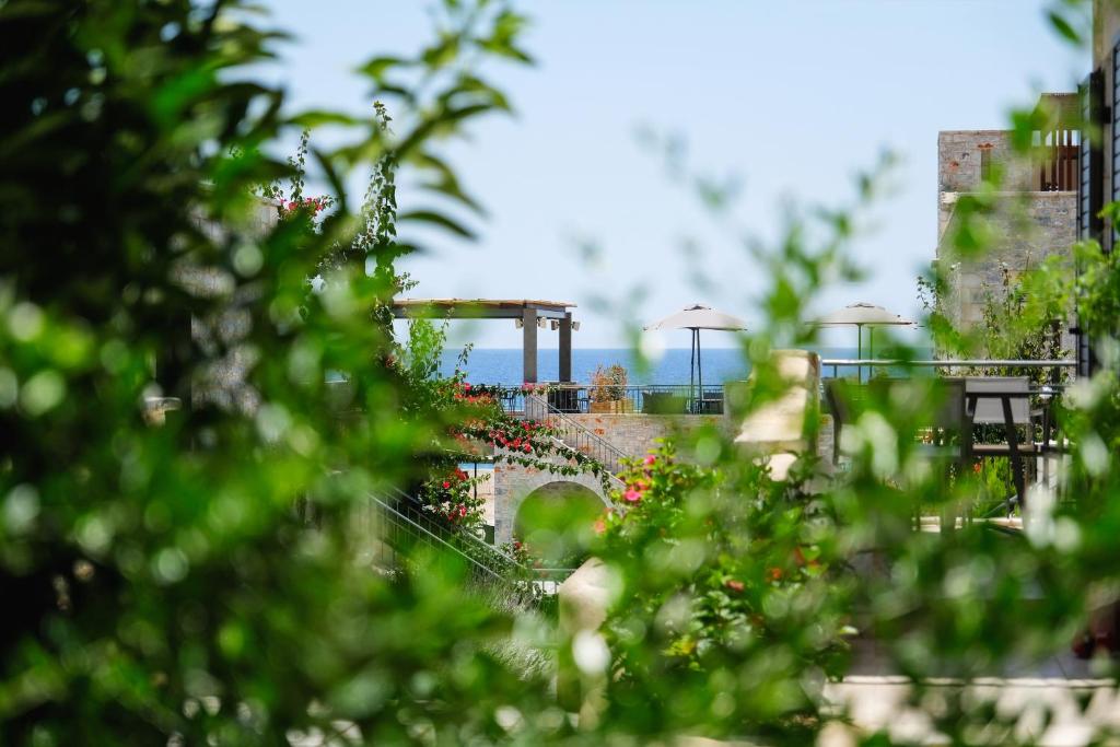 a garden with flowers and a bridge in the background at Margo Beach Hotel in Gythio