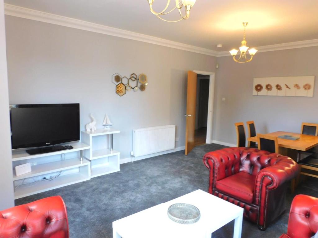 a living room with red furniture and a flat screen tv at City Centre 2 bedroom apt, close to M8 & Tourist Attractions in Glasgow
