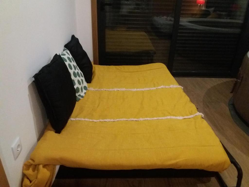 a yellow bed with black pillows on top of it at Suitebangalo ponte 516 e passadiços do paiva in Cinfães