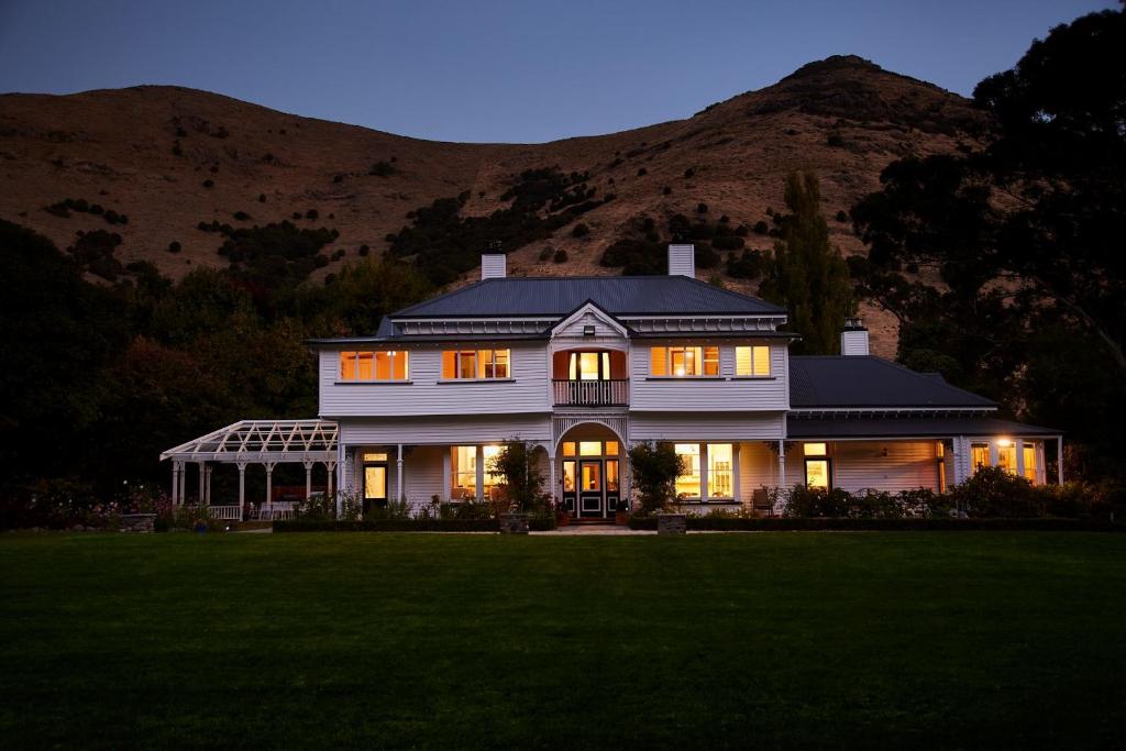 uma grande casa branca com uma montanha ao fundo em Kaituna Valley Homestead em Little River