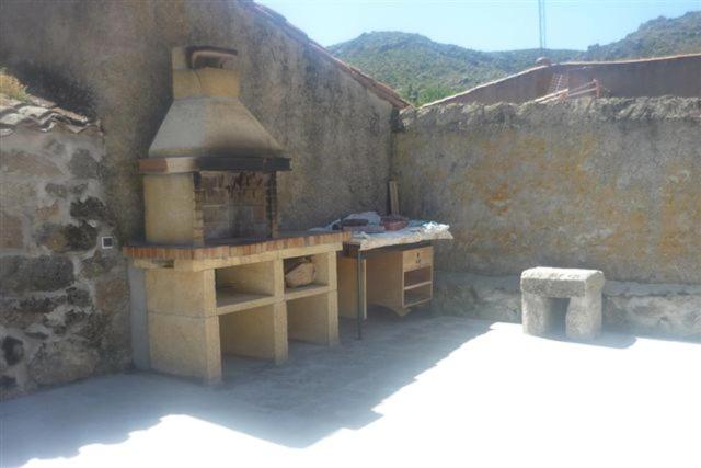 uma cozinha exterior com um fogão numa parede de pedra em Casa Rural La Fortaleza em Escalonilla
