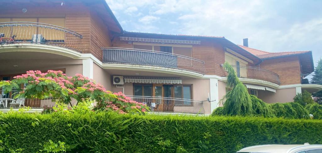 a large house with a balcony and pink flowers at Selyemakácapartman in Balatonlelle