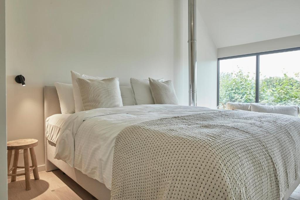 a white bedroom with a large bed with a window at La Cigogne Boutique Suites in Retranchement