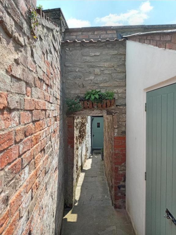 un callejón en un antiguo edificio con una puerta verde en Delighful self catering in the heart of Glastonbury, en Glastonbury