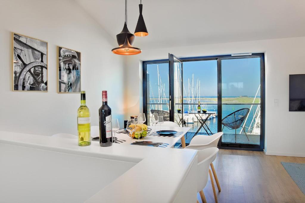 a white kitchen with a table with wine bottles at Captain's Home Heiligenhafen in Heiligenhafen