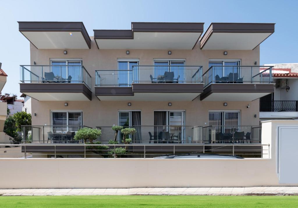 un edificio de apartamentos con balcones, mesas y sillas en Crist Luxury Apartments, en Nea Potidaea