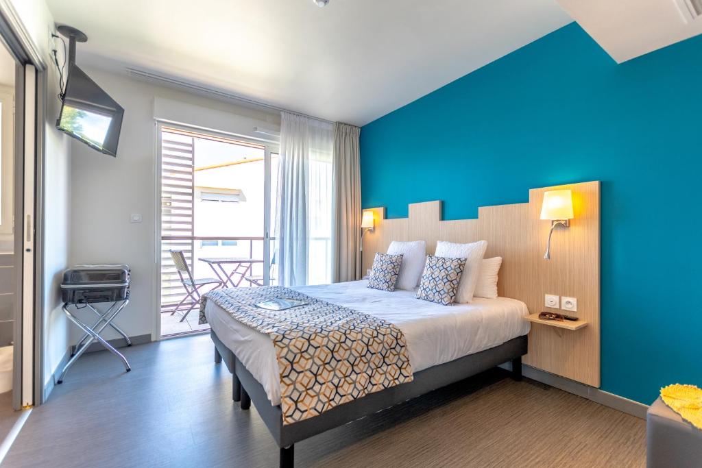 a bedroom with a large bed with a blue wall at Hotel Le Virevent in Saint-Raphaël