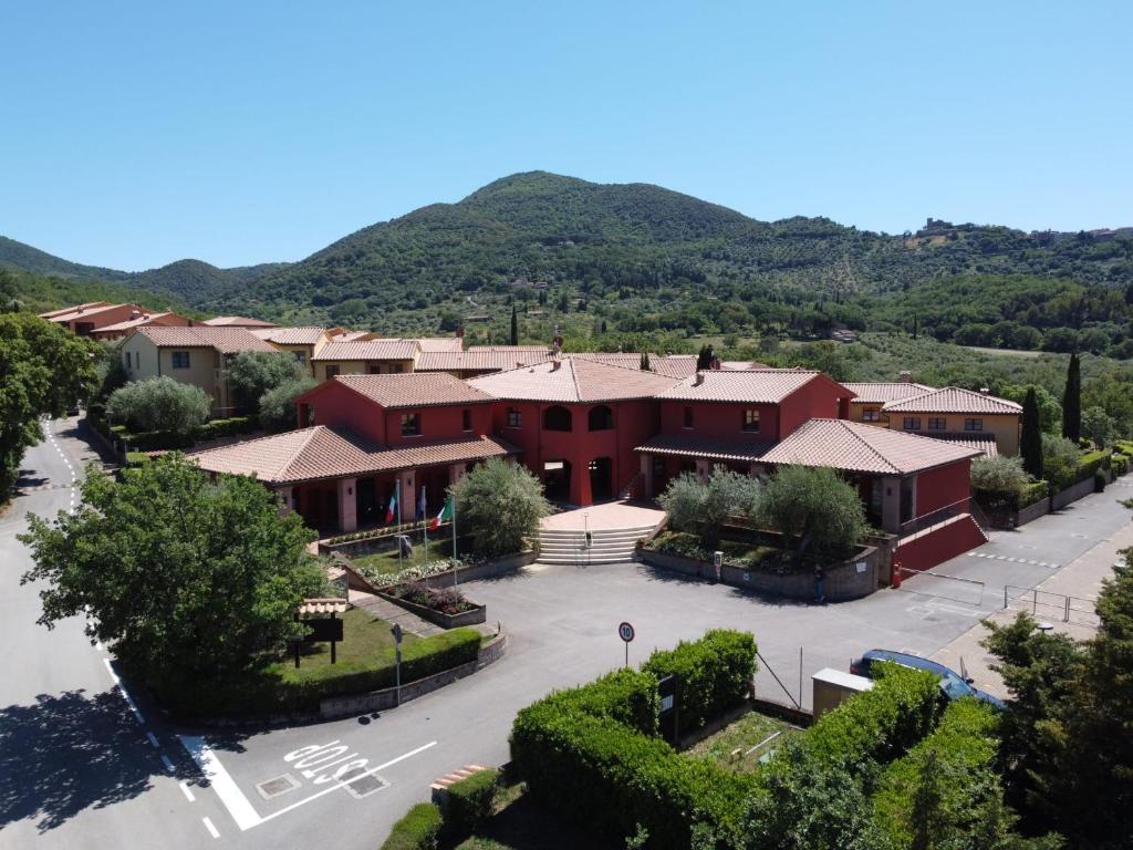 une vue aérienne sur un bâtiment rouge avec un parking dans l'établissement Borgo Etrusco, à Scarlino