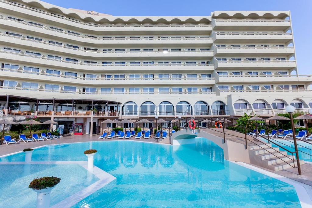 a hotel with a large swimming pool in front of a building at OLYMPOS BEACH HOTEL in Faliraki