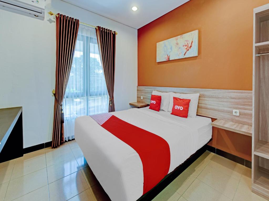 - une chambre avec un grand lit et des oreillers rouges dans l'établissement Capital O 90497 Navaya Guest House, à Banyumas