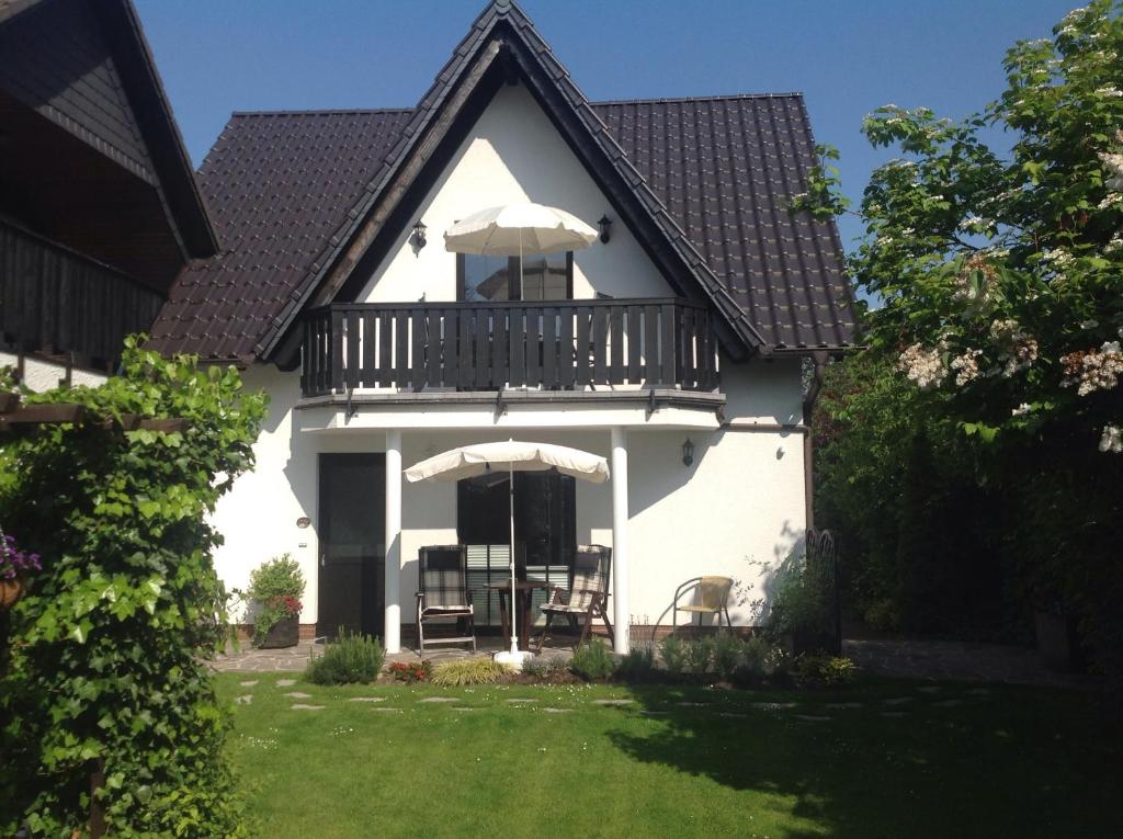 a white house with a balcony and some chairs at Haus Kollwitzweg - Ferienwohnungen in Goslar