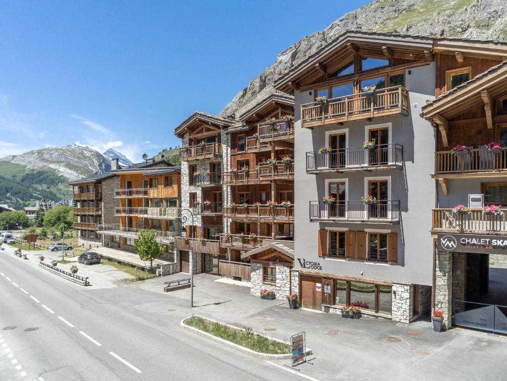 an apartment building on a street with a mountain at Victoria Lodge, Friendly Hotel in Val-d'Isère