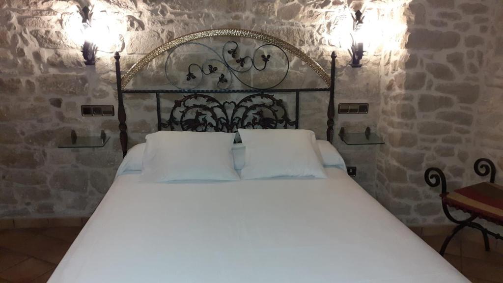 バルデロブレスにあるHOTEL EL CASTELLの石壁のベッドルーム1室(白い大型ベッド1台付)