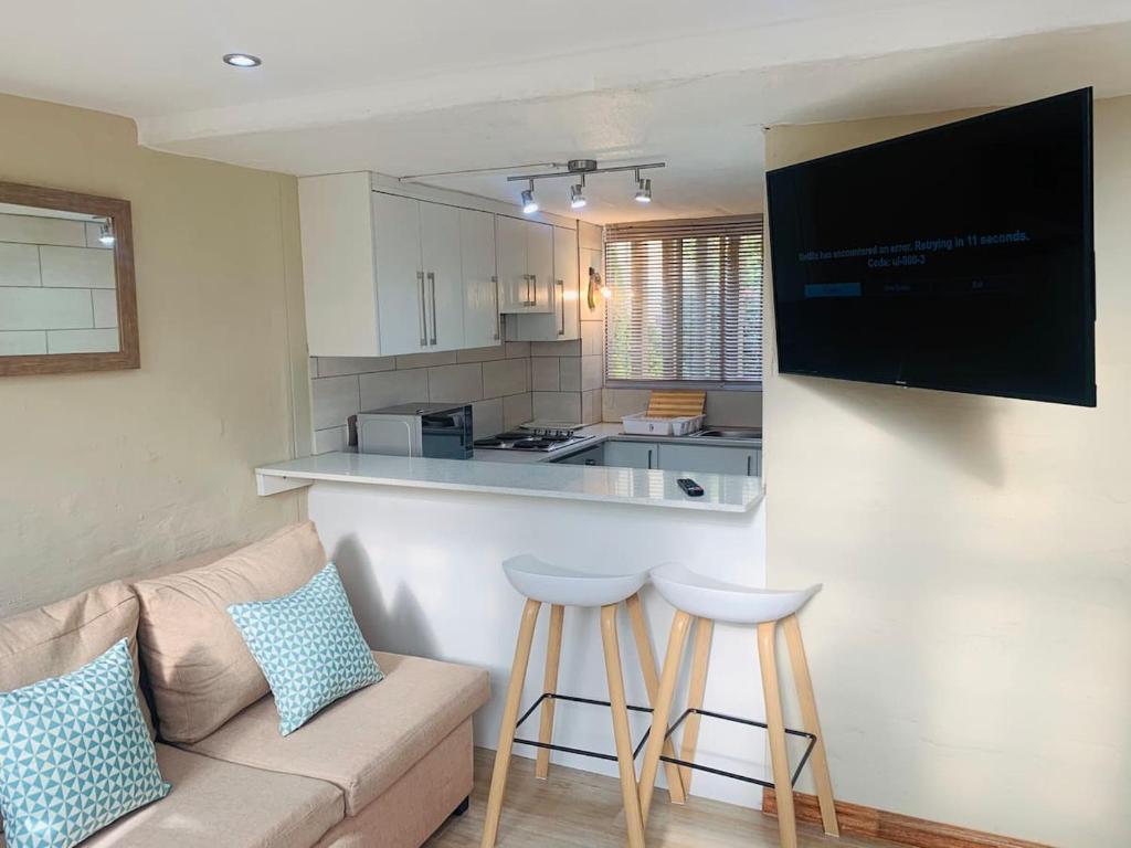 uma sala de estar com um sofá e uma cozinha em The Loft@Santorini em Pretoria