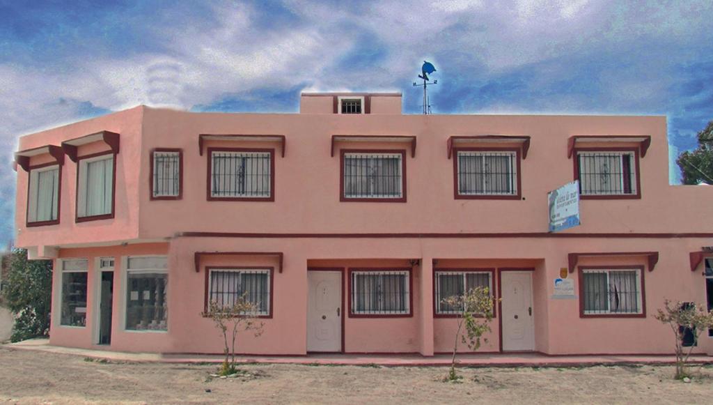 a pink building with trees in front of it at Complejo Veleta de Mar in Las Grutas