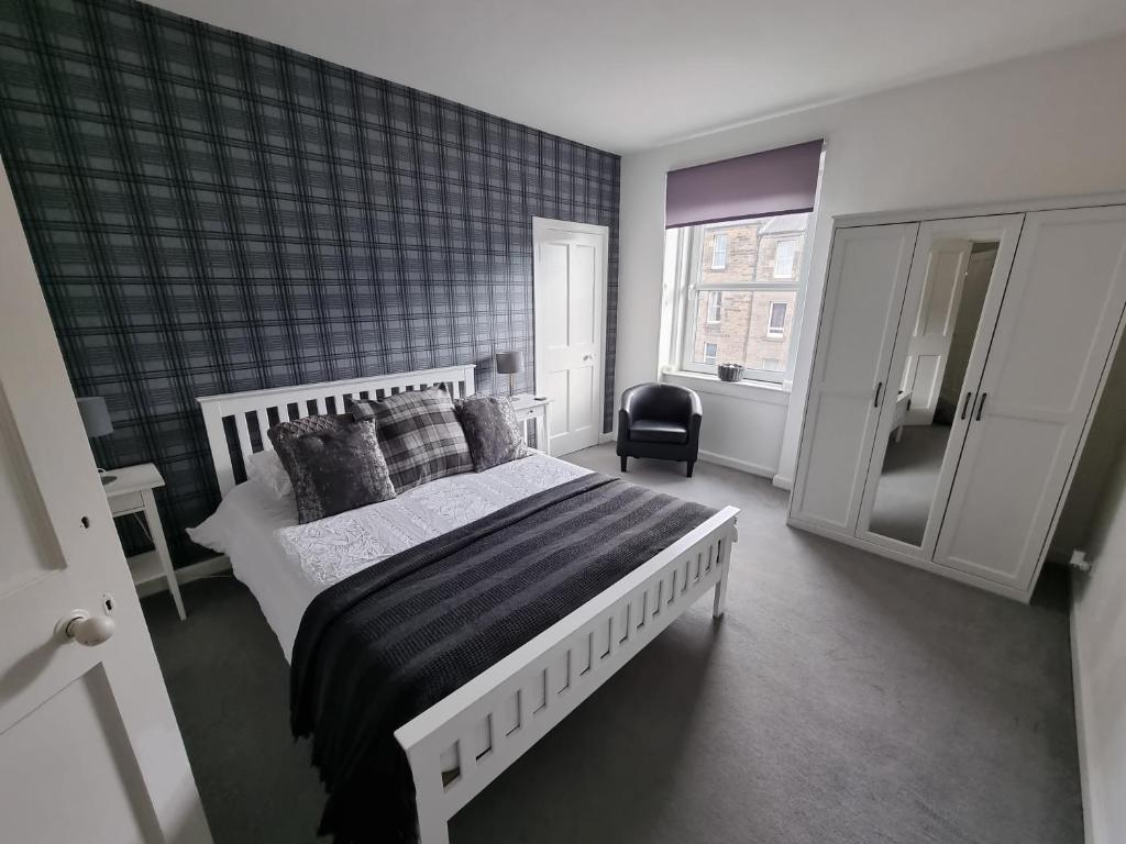 um quarto com uma cama grande e uma cadeira em Bespoke Tours Scotland Accommodation @ Morrison Street em Edinburgo