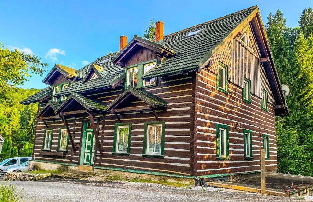 a wooden house with green windows and a car parked in front at Penzion Zelené Údolí in Janske Lazne