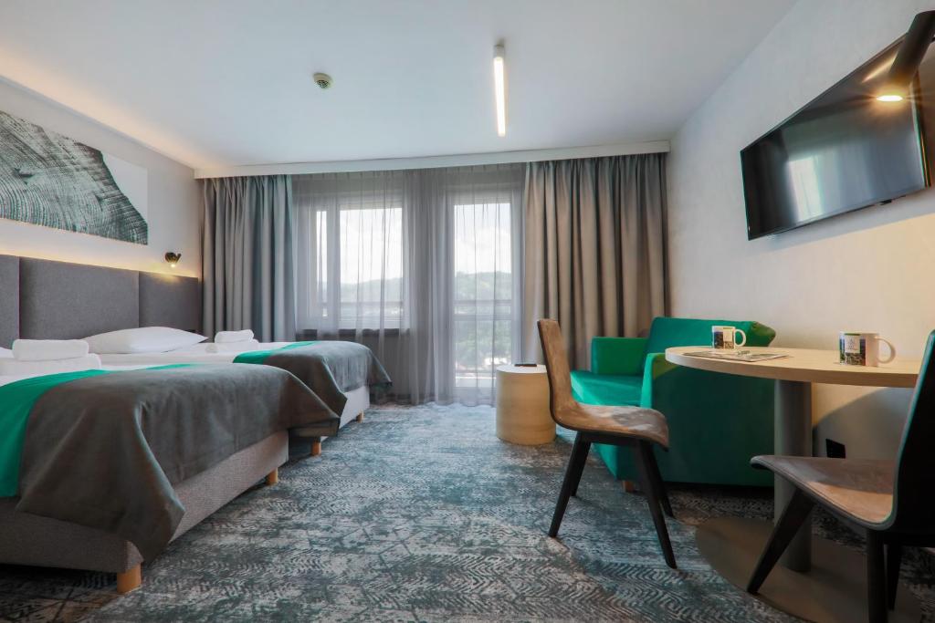 um quarto de hotel com duas camas e uma mesa e cadeiras em Hotel Pod Jedlami em Wisla