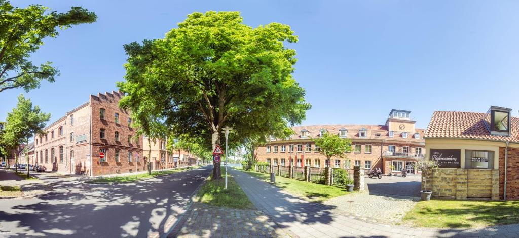 an empty street with a tree and buildings at Hotel Hafenresidenz Stralsund in Stralsund