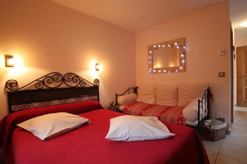 een slaapkamer met 2 bedden met rode lakens en een spiegel bij Résidence Chardon Bleu in Landry