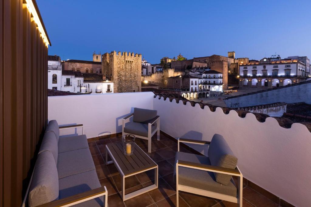 balcón con sillas, mesa y vistas en Apartamentos El Patio Plaza Mayor Cáceres, en Cáceres