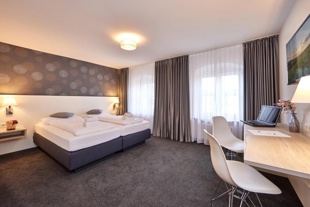 een hotelkamer met een bed en een bureau met een laptop bij Hotel Alter Wirth in Geretsried