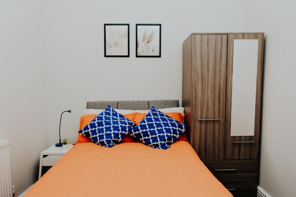 Schlafzimmer mit einem Bett mit blauen und orangefarbenen Kissen in der Unterkunft Regent park House in Etruria